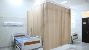 Hospital room with a single patient bed and beige privacy curtains