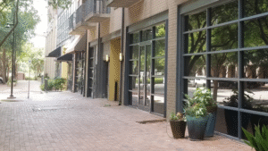 Row of retail storefronts with crystal-clear glass windows and planters.