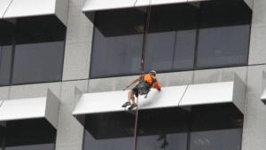  Professional cleaner suspended on ropes washing windows of a high-rise building.
