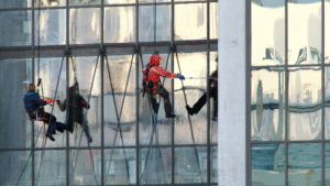 Technicians performing high-rise window cleaning on a glass building