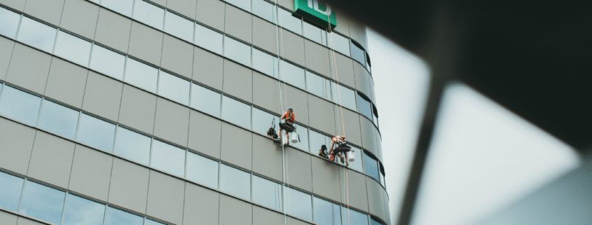 Window cleaning team working on a tall commercial glass building