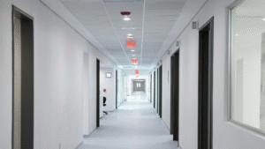 Long hospital hallway with white walls and red exit signs.