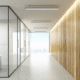 Empty corporate hallway with glass office partitions and wood accent wall.