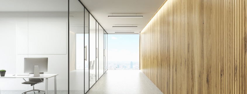 Empty corporate hallway with glass office partitions and wood accent wall.