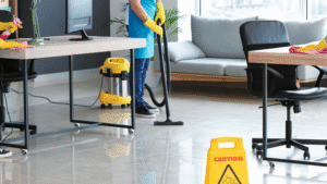 Cleaner vacuuming floors in a Chicago office with caution sign.