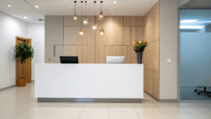 Modern reception desk with clean white counter, wood panels, and fresh flowers.