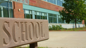 Exterior of a school building with a stone sign reading “SCHOOL.
