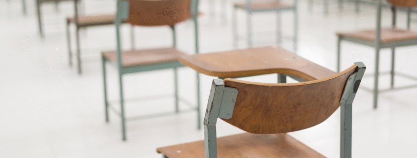 Empty classroom with old wooden desks and chairs.