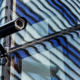 Security camera mounted on a glass building window with streaks.