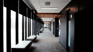 Clean commercial hallway with large windows, black frames, and soft seating