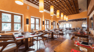Elegant restaurant interior with orange walls, wood tables, and soft light