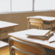 Clean classroom desks with notebooks and pencil under morning light