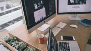 Clean modern office desk with monitors, laptop, and indoor plants