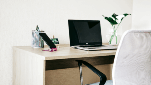 Minimalist workstation with laptop, chair, and plant in clean office