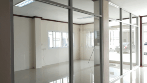 Clear glass-walled office with bright natural light and polished floors