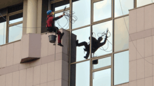 Window cleaning technicians working at height on glass building.