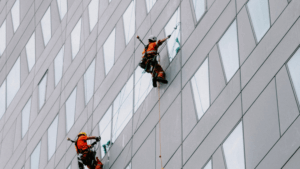 Two professionals scaling glass exterior of a commercial high-rise.
