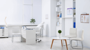 Modern medical exam room with white decor, desk, and treatment table