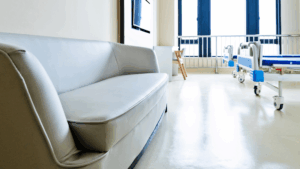 Clean hospital recovery room with patient bed and seating area prepared for post-surgery care