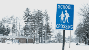 School crossing sign surrounded by snow in winter