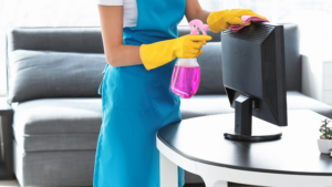 Commercial cleaner disinfecting a computer monitor in a modern office workspace