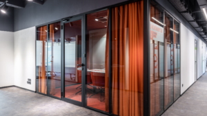 Private executive office with tidy desk, indoor plants, and clean glass partitions.