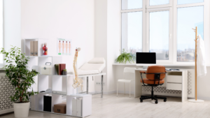 Bright medical exam room with desk, exam table, and large window