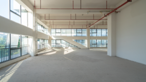 Empty commercial space after construction with large windows and exposed ceiling pipes