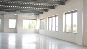 Bright interior with drywall, exposed ceiling, and unfinished commercial flooring
