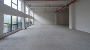 Large empty commercial floor with windows and visible dust on concrete surface