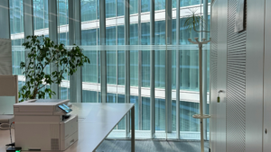 Office workspace with desk, printer, and large windows