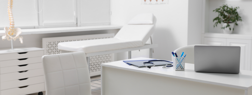 Clean medical exam room with bed, desk, and organized equipment