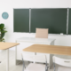 Clean classroom with organized desks and green board ready for students