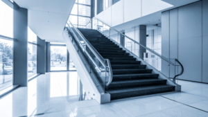 Large commercial staircase with glass railings and natural light