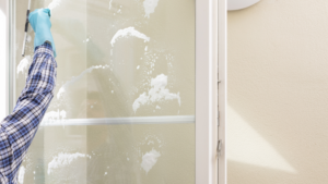 Window cleaner removing soap and buildup from commercial glass door.