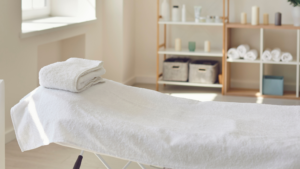 Clean treatment bed with folded towel inside a controlled healthcare environment.