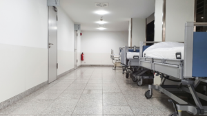Hospital hallway with patient beds inside a clean medical facility corridor.