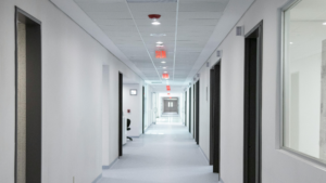 Bright healthcare hallway with clean floors and organized patient room access points.
