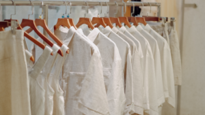 Neutral clothing collection displayed on wooden hangers inside a clean retail store.