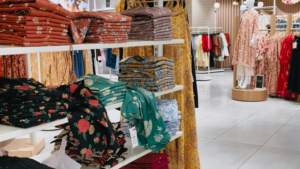 Folded clothing displays arranged neatly inside a bright retail fashion store.