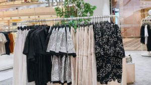 Clothing rack with neatly organized apparel inside a shopping mall retail space.