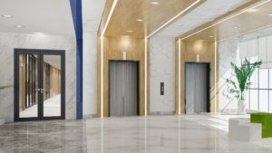 Bright commercial building lobby with large staircase, glass walls, and polished floors.