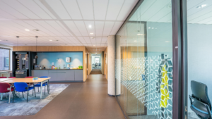 Clean office hallway with glass partitions, break area, and organized workspace maintained through routine cleaning.
