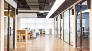 Office hallway with glass conference rooms, polished floors, and modern lighting.