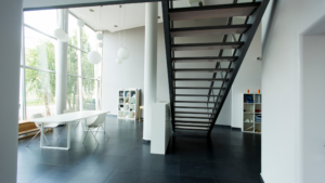 Modern office lobby with staircase, large windows, and clean polished floors.