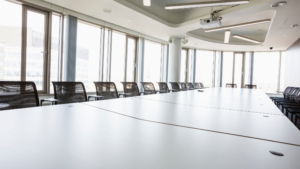 Large conference room with clean tables, chairs, and floor-to-ceiling windows.