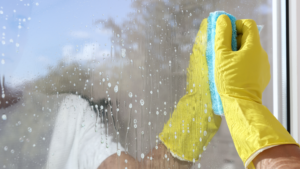 Close-up of window cleaning process using microfiber cloth and cleaning solution.