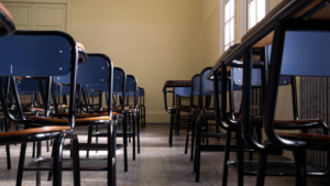Bright classroom with desks and large windows during the summer break.