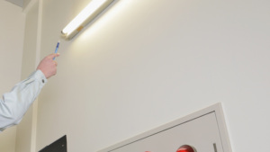 Maintenance technician checking commercial lighting inside an office building.