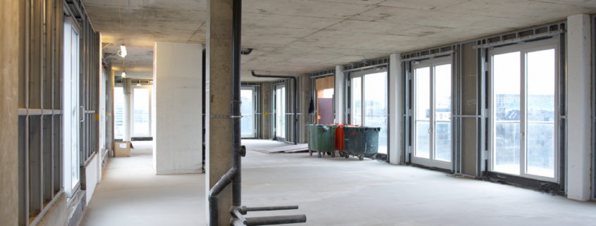 Commercial renovation project before final construction cleaning with exposed concrete and construction materials.